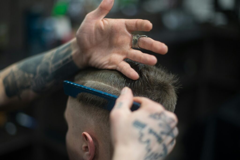 pexels-photo-1570807-1570807 Close-up of a tattooed barber giving a stylish haircut indoors, highlighting modern grooming techniques.